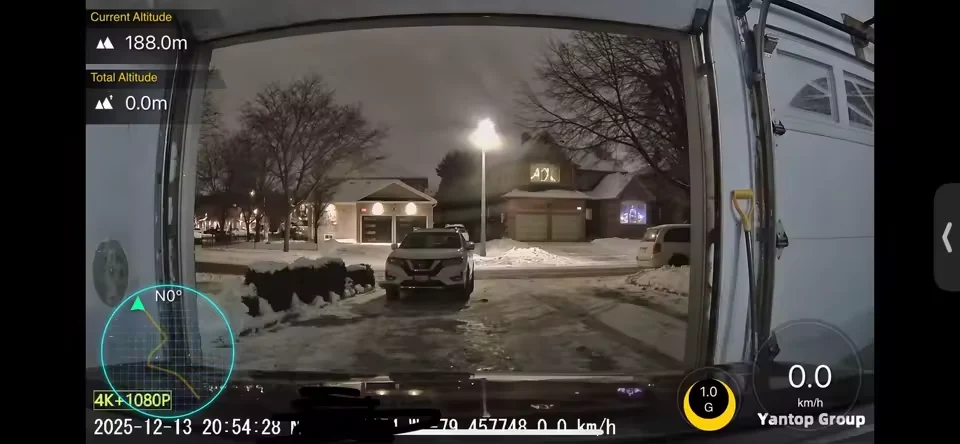 Dash cam night footage of a snowy street under streetlight